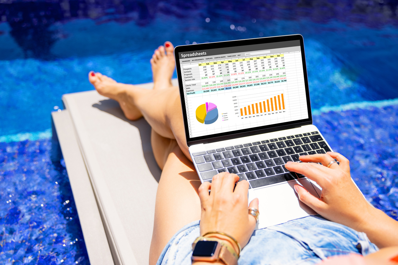 Woman Working on Laptop Computer While Relaxing by the Pool Outdoors